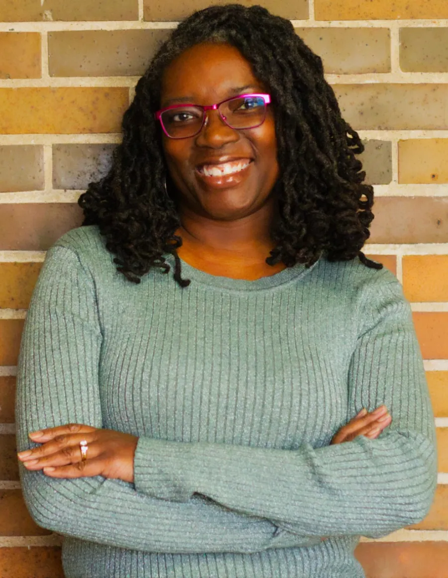 a woman standing in front of a brick wall